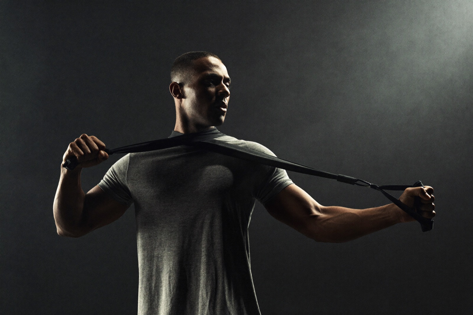 Athlet trainiert mit Widerstandsband im abgedunkelten Trainingsraum